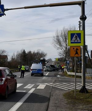 Wypadek drogowy, miejscowość Trześń. Zdarzenie dwóch pojazdów toyoty yaris i opla. na miejscu policjanci wyjaśniają okoliczności zdarzenia. na zdjęciu widoczne samochody, jadące ulicą.