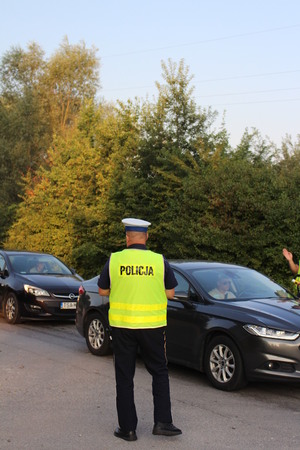 Policjant ruchu drogowego podczas służby na drodze nadzoruje bezpieczeństwo kierujących pojazdami.