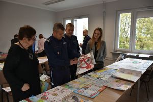 Jury konkursu plastycznego &quot;Bezpieczne wakacje&quot; wyłania najlepsze prace i ich laureatów. 
 Komendant Miejski Policji w Tarnobrzegu mł.insp. Marek Pietrykowski trzyma prace plastyczną - stop narkotykom!