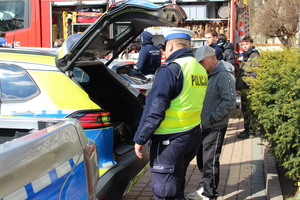 na zdjęciu widoczny funkcjonariusz Policji oraz mężczyzna oraz tylna cześć radiowozu