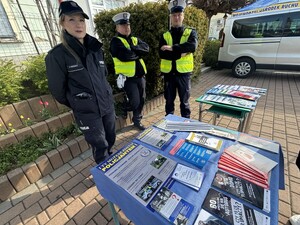 na zdjęciu widoczni funkcjonariusze Policji oraz stoisko z ulotkami